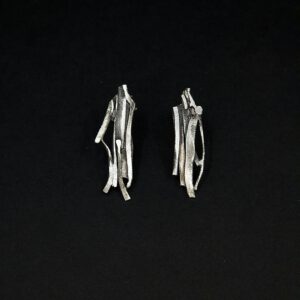 Handgefertigte Silberohrringe, deren Struktur an geschichtete Felsen erinnern.