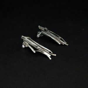 Handgefertigte Silberohrringe, deren Struktur an geschichtete Felsen erinnern.