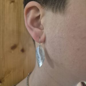 Handgefertigte Silberohrringe in Blattform am Ohr getragen