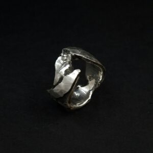 Handgefertigter Silberring, dessen Struktur an Felsen erinnern.