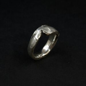 Handgefertigter Silberring, dessen Struktur an Felsen erinnern.