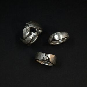 Drei Handgefertigte Silberringe, deren Struktur an Felsen erinnern.