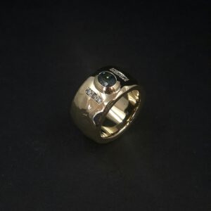 Handgearbeiteter Goldring mit blauem Kundendiamant und sechs weißen Brillanten.