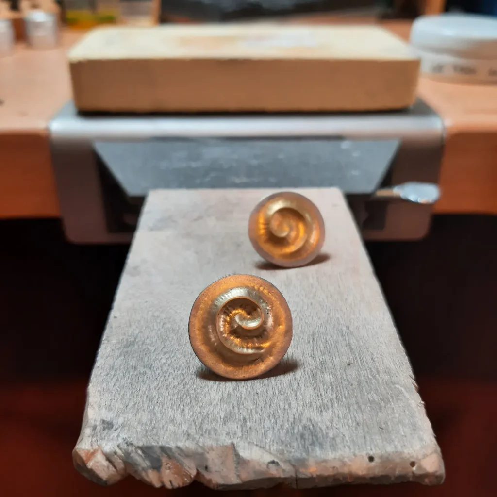 Rundes, handgefertigtes Ohrsteckerpaar aus Gold mit Platinrand. Auf der Flache ist eine erhabene Spirale, die auf beiden Ohrsteckern entgegengesetzt verlaufen.